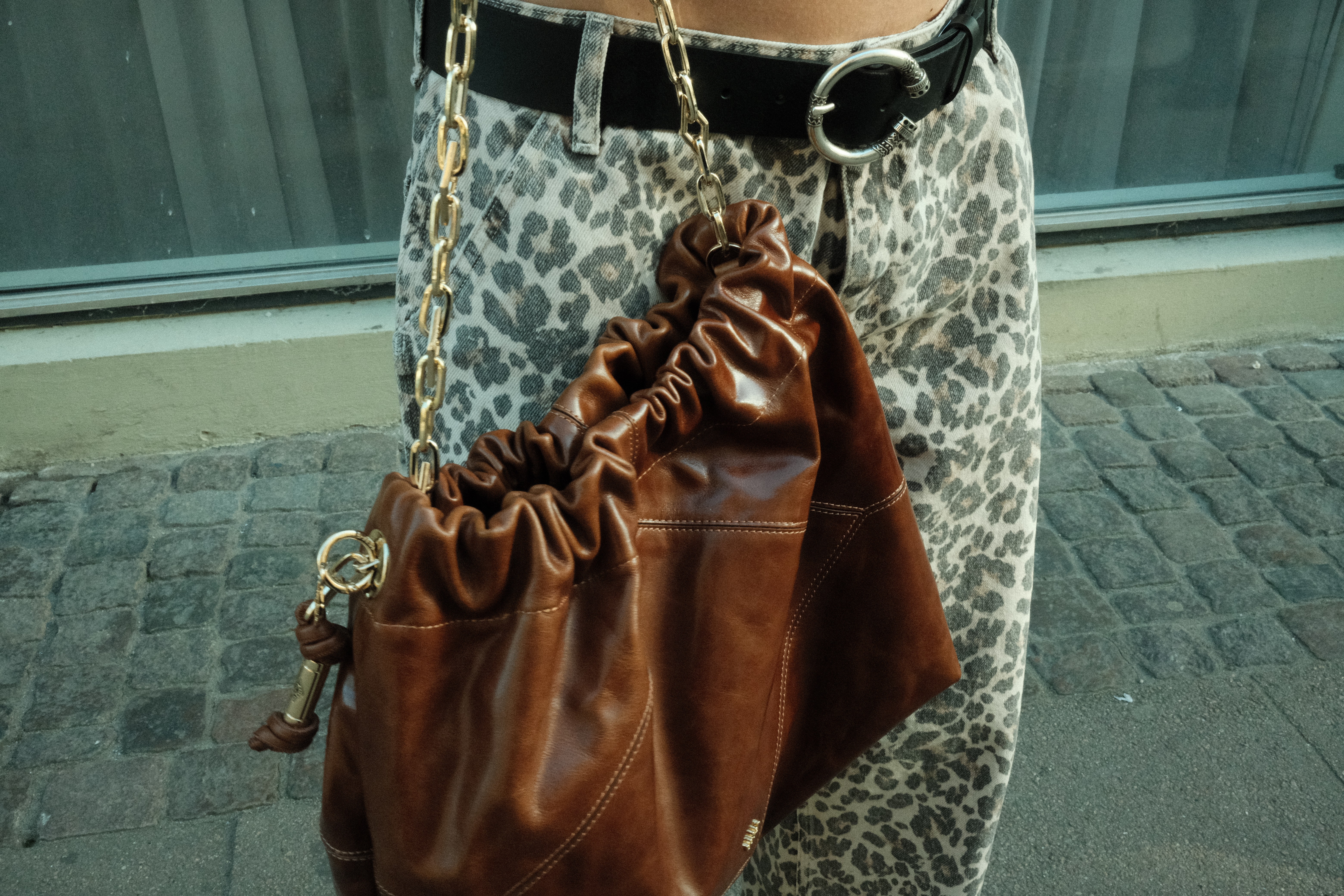 Backside of a person with a had and curly hairs sits in front of a screen in a room