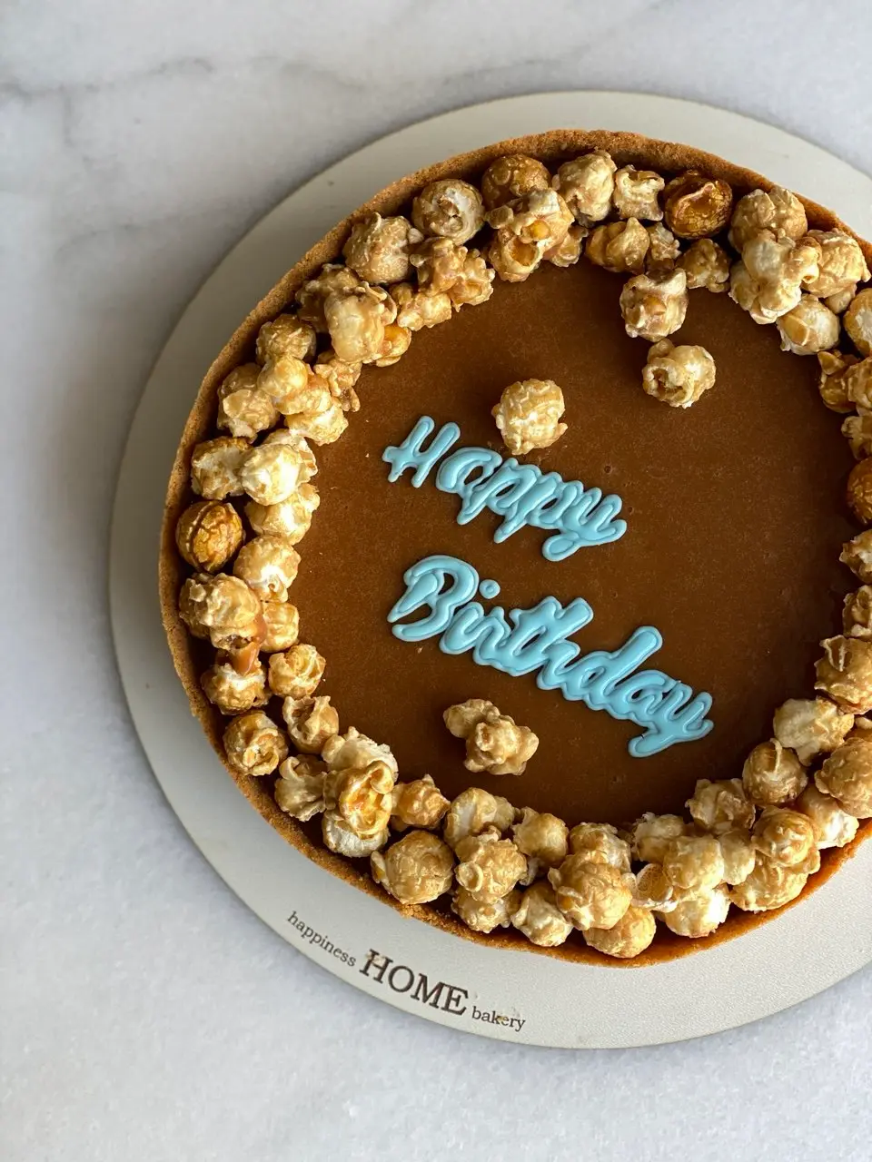 Chocolate cheesecake with "Happy Birthday" blue message and popcorn border