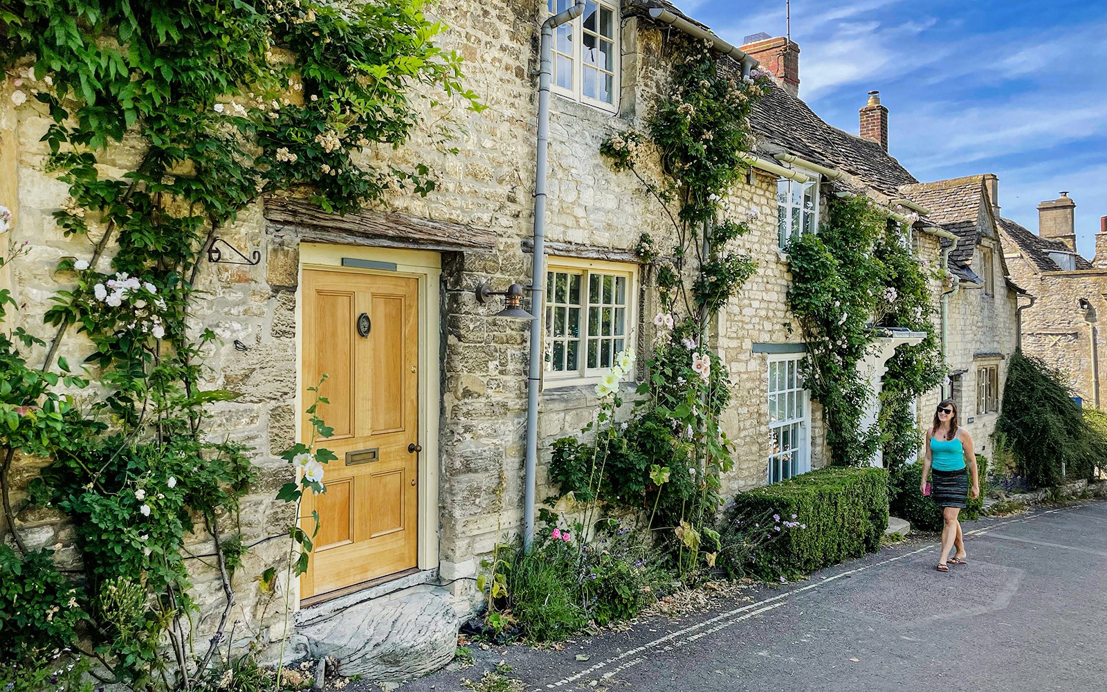 科茨沃茲的石頭小屋,爬藤植物環繞,旁邊有一位行人。