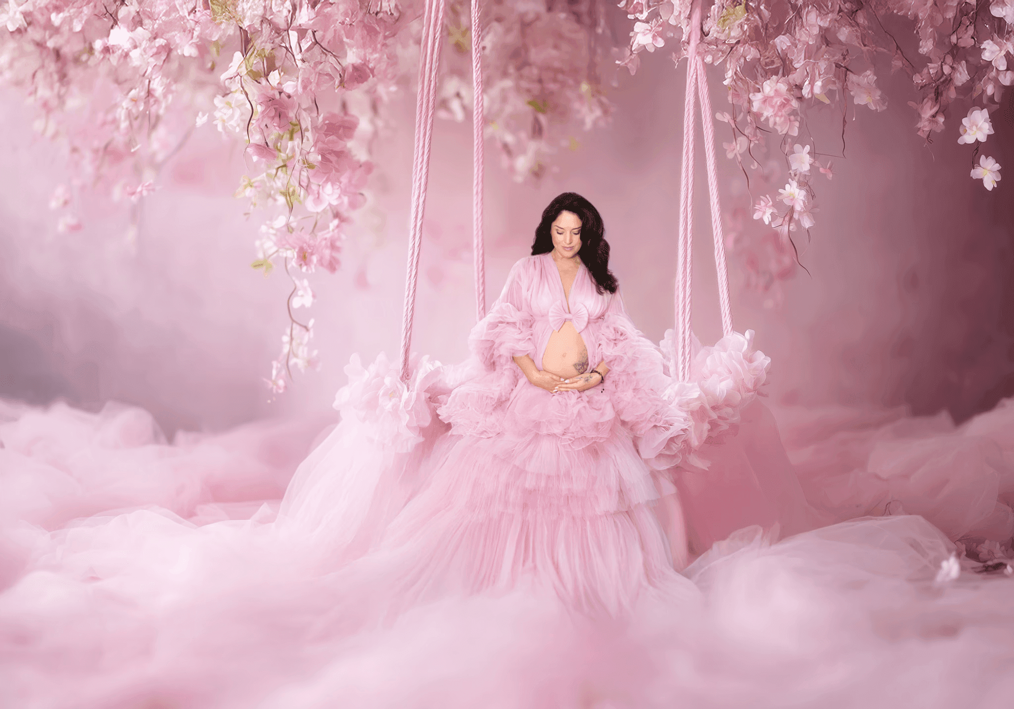 A glowing mother-to-be in a ruffled pink gown, captured in a maternity shoot Dubai against a floral backdrop.