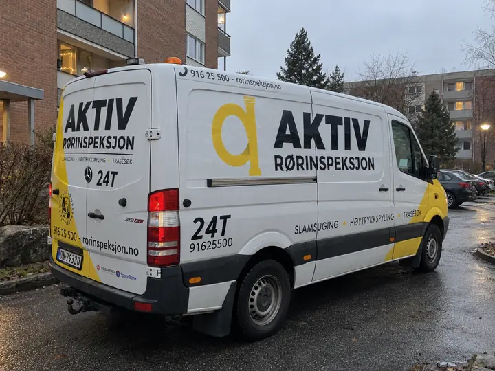 Hvit Aktiv-varebil parkert foran borettslagsbygg.