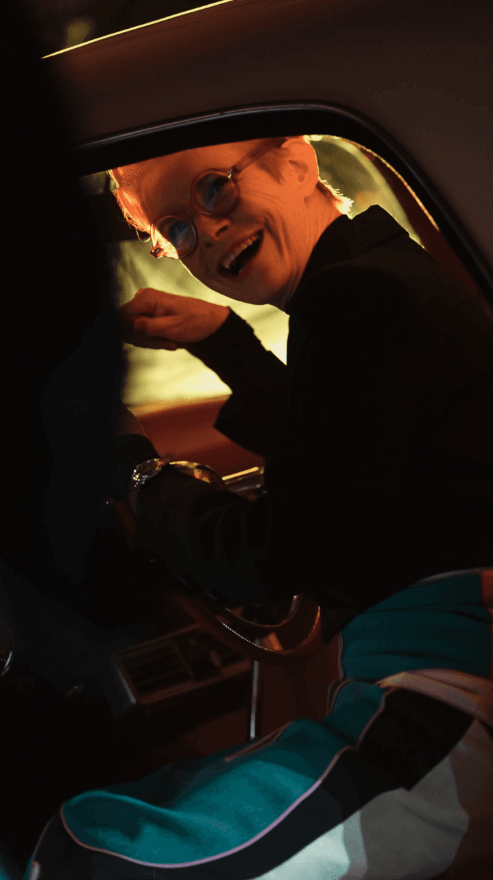 Bride sitting on ground against wall, groom standing nearby