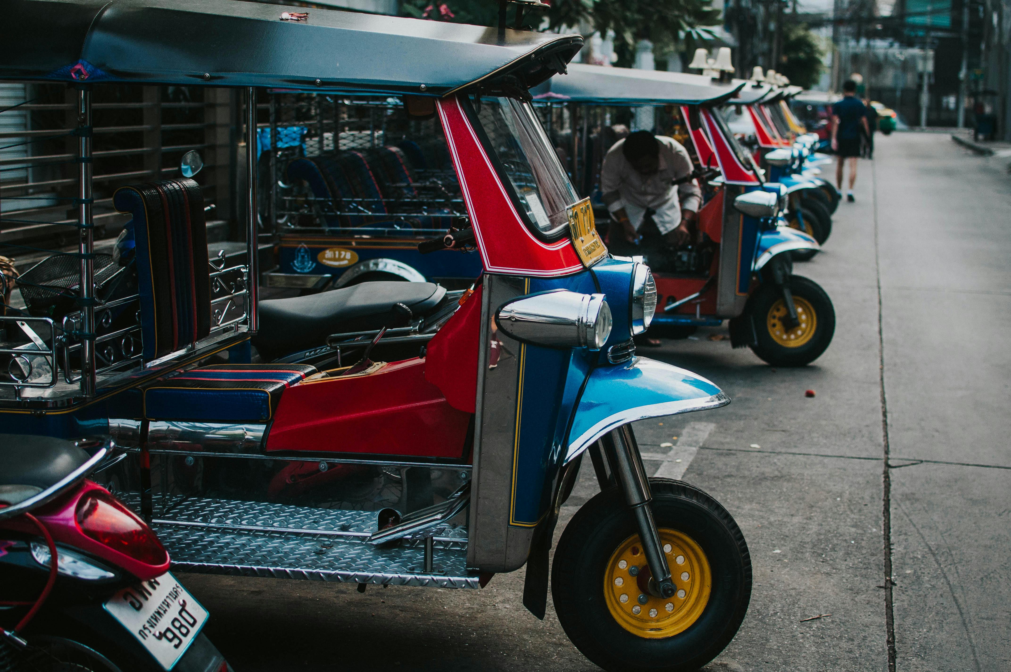 a blue and yellow tuk tuk driving down a street
