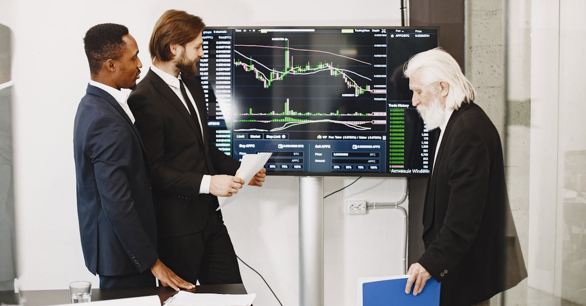 Three businessmen analyzing financial charts on a screen in an office setting.