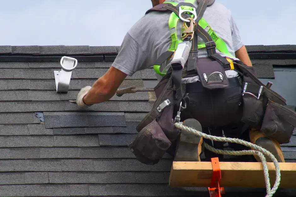 closeup photo of roofer repairing shingles at water leak location