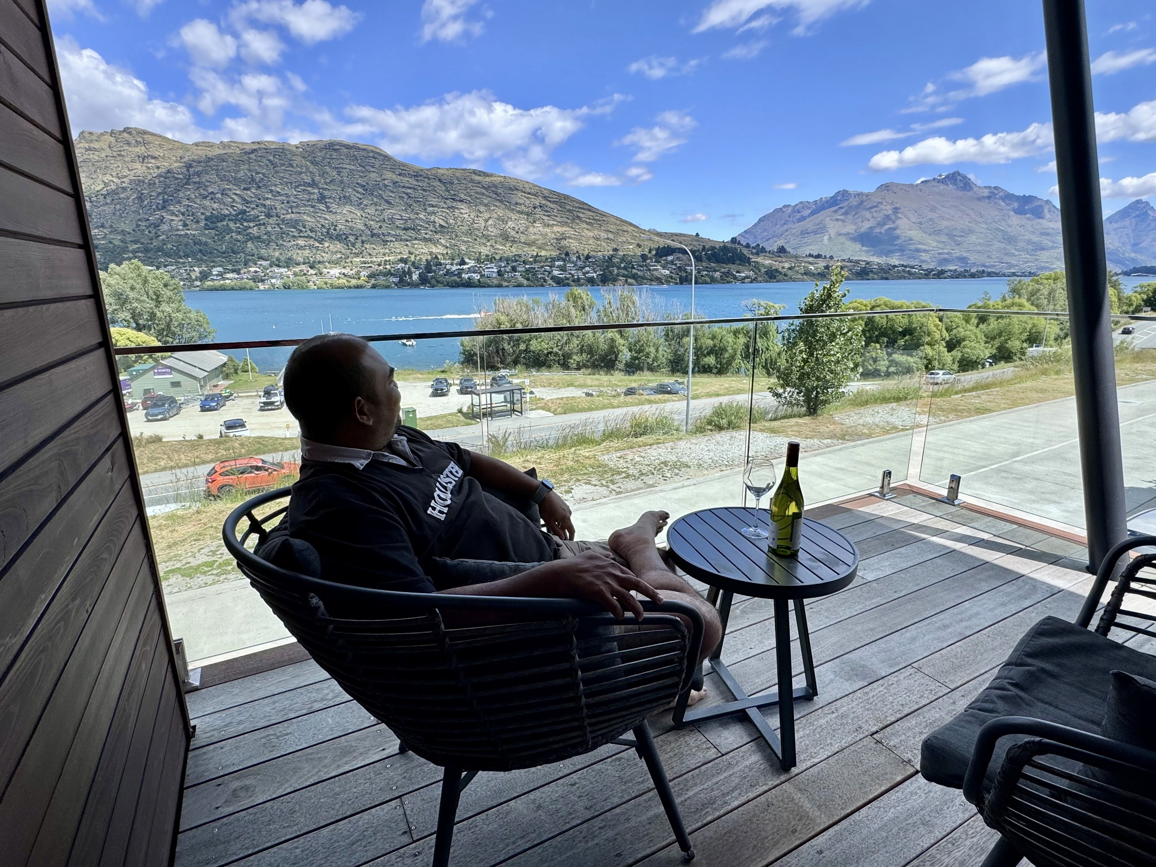 The  breathtaking views from our AirBnB in Queenstown. Seated on a chair with wine in hand, the person is enjoying the views.