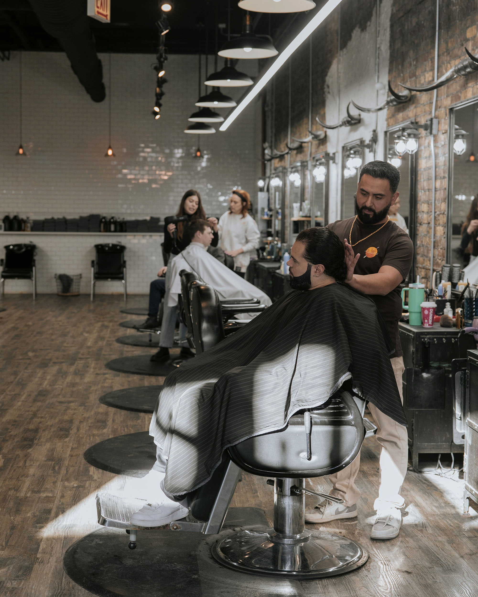 Interior view of Old Town Barber in Chicago during active grooming sessions, highlighting the relaxed atmosphere and craftsmanship of the barbers at work.