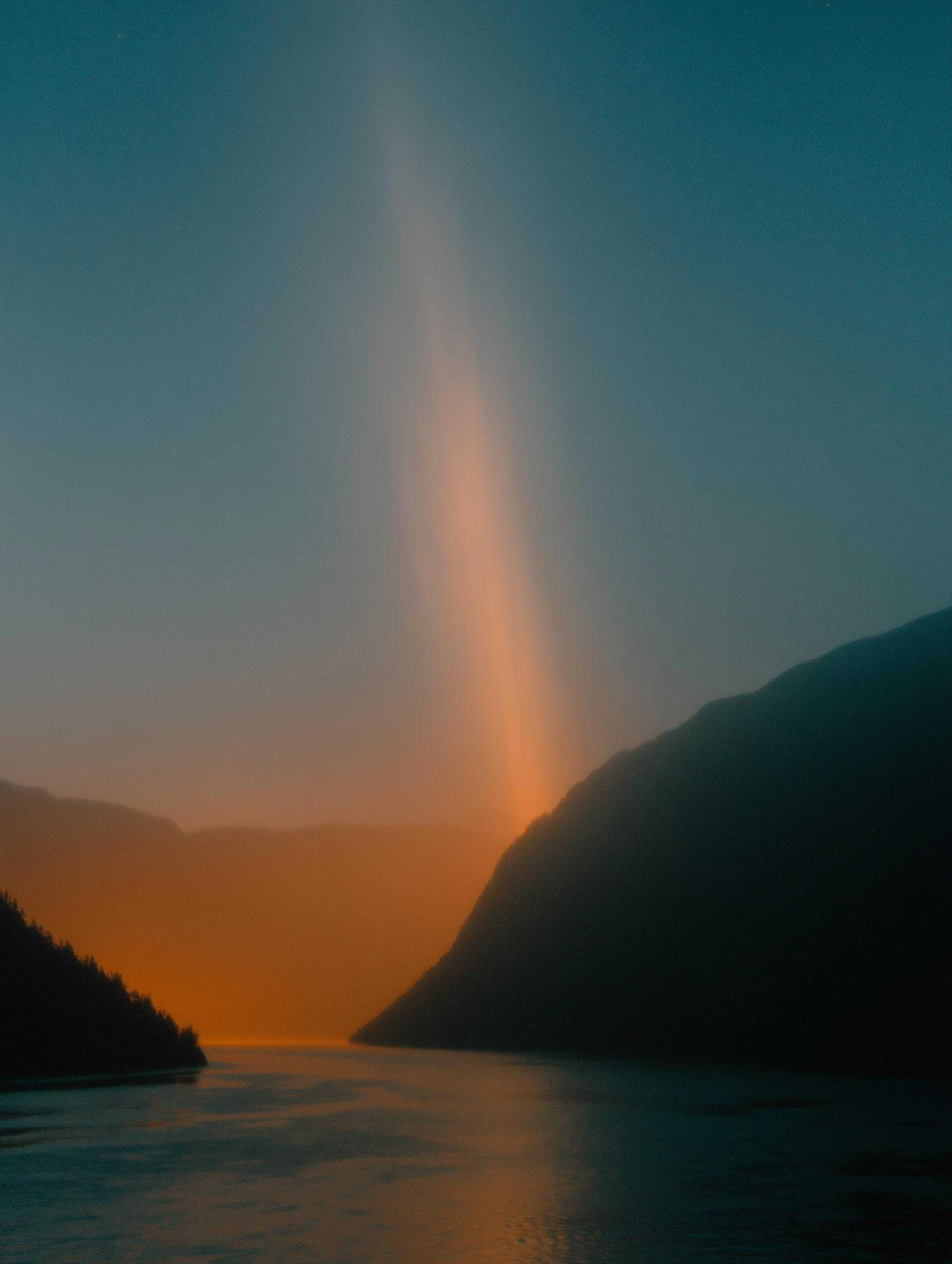 Golden sun ray beam through mountains onto water