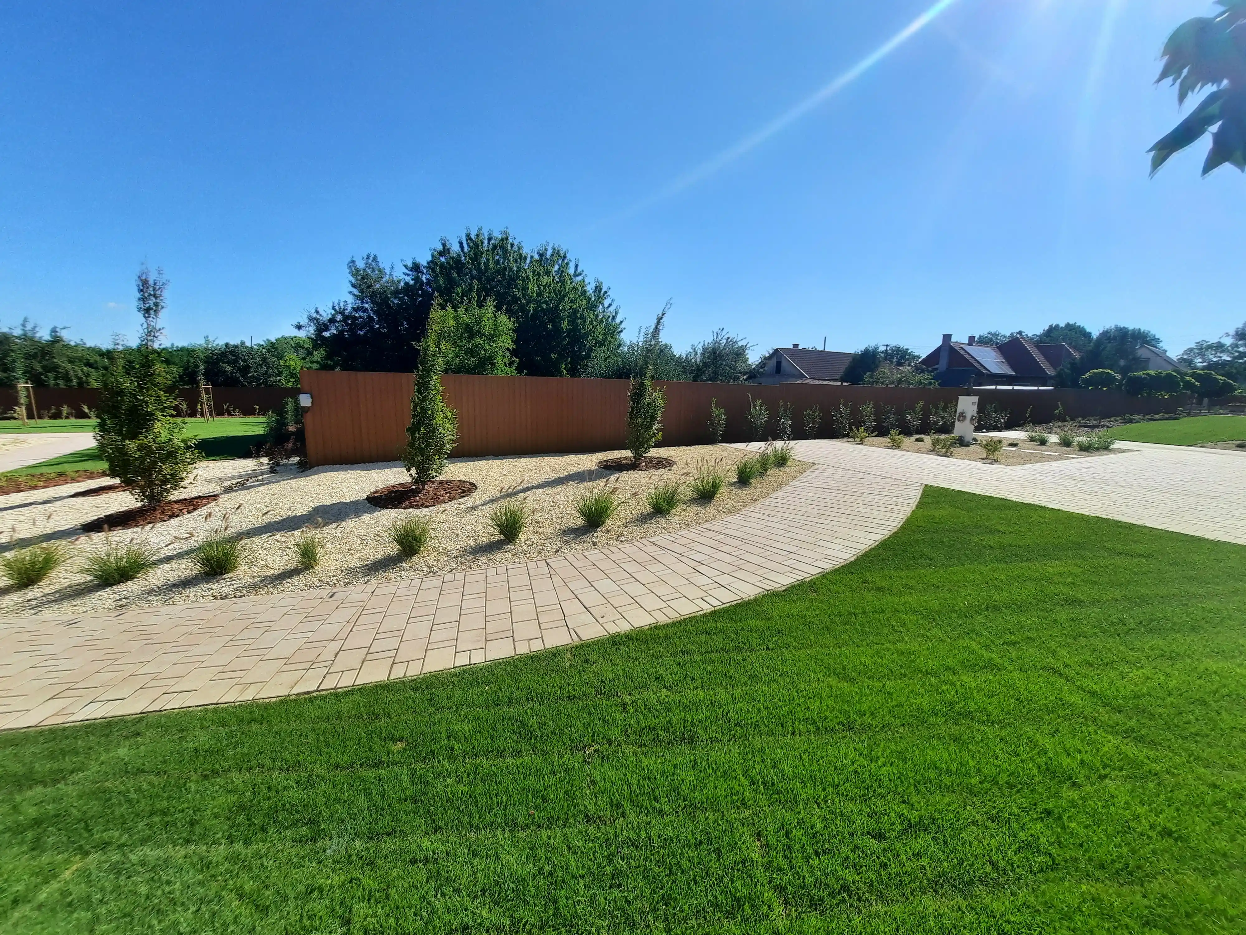 Parkosított közterület íves sétánnyal és oszlopos fákkal