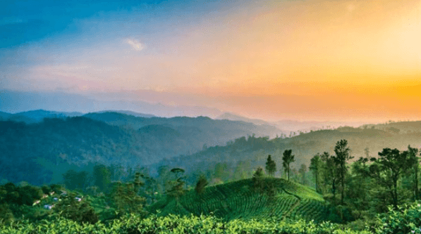 A serene landscape showing rolling hills under a vibrant sunrise, with misty mountains in the background.