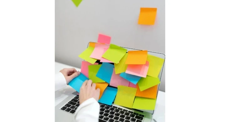 Laptop coberto de post-its coloridos, com uma pessoa digitando