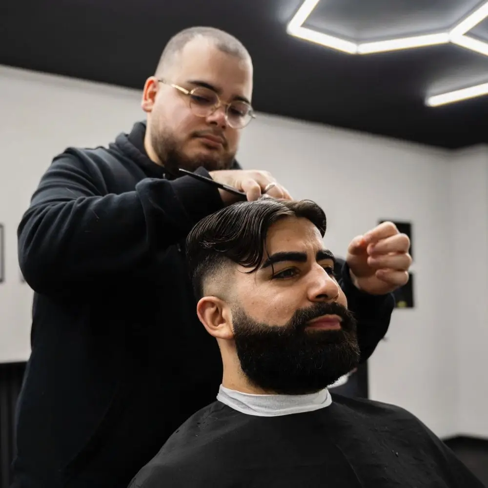 Barber die een klant aan het knippen is in een kapsalon