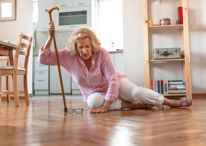 Elderly woman fallen on floor reaching for cane at home.