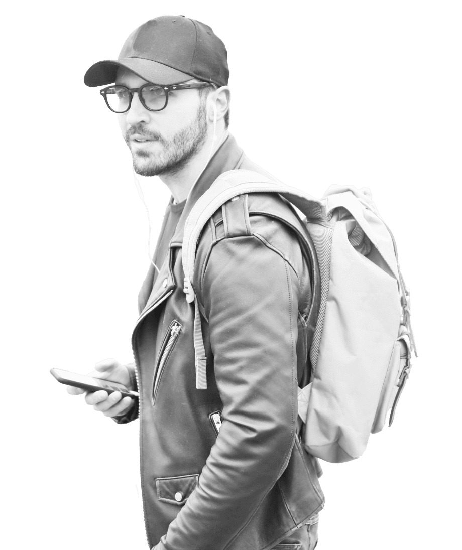 A person wearing a leather jacket, a cap, and sunglasses, carries a backpack and holds a smartphone with earphones, appearing to walk and listen to something.