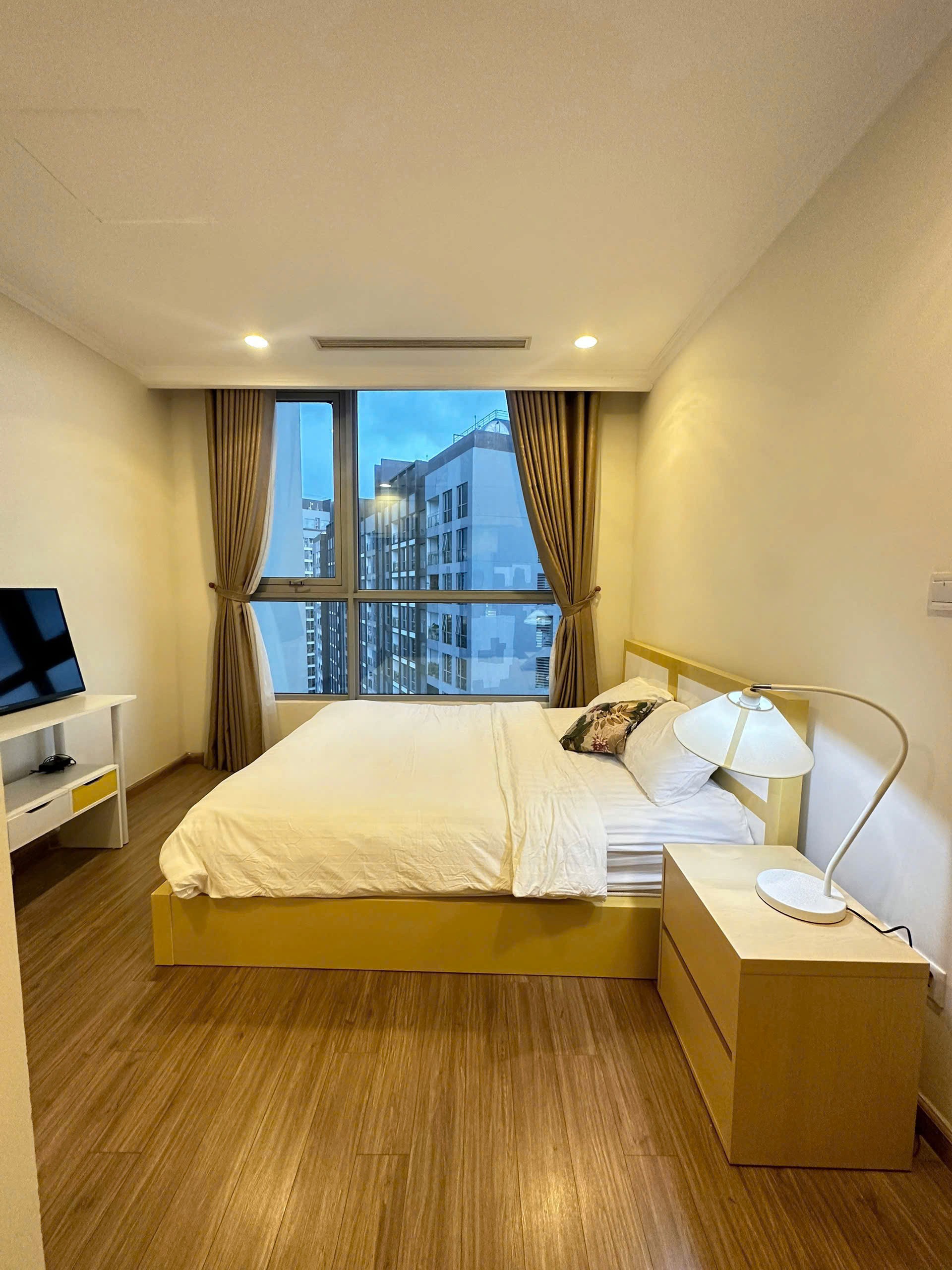 Phòng ngủ hiện đại với tông màu trung tính, giường platform và TV treo tường.