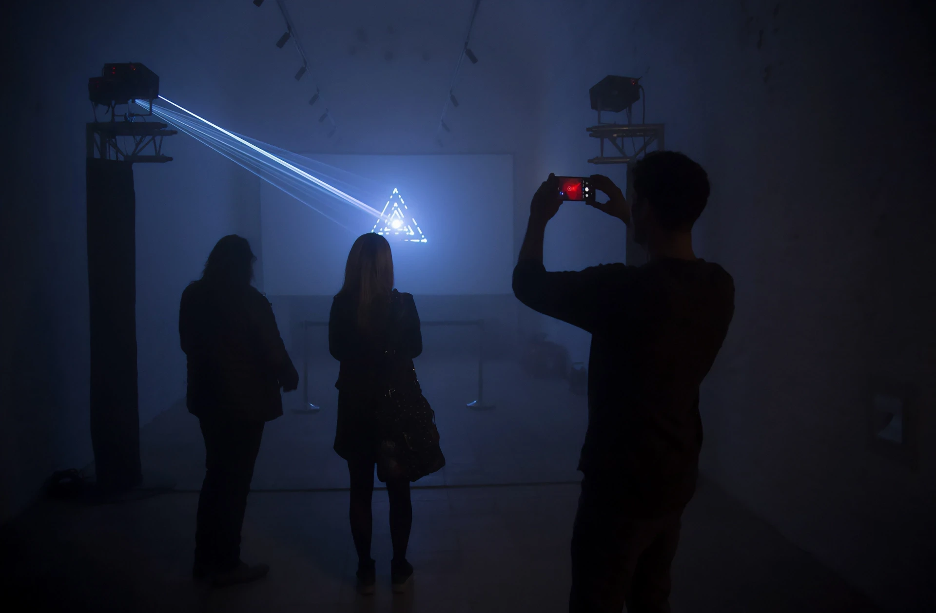 People watching light installation with phone