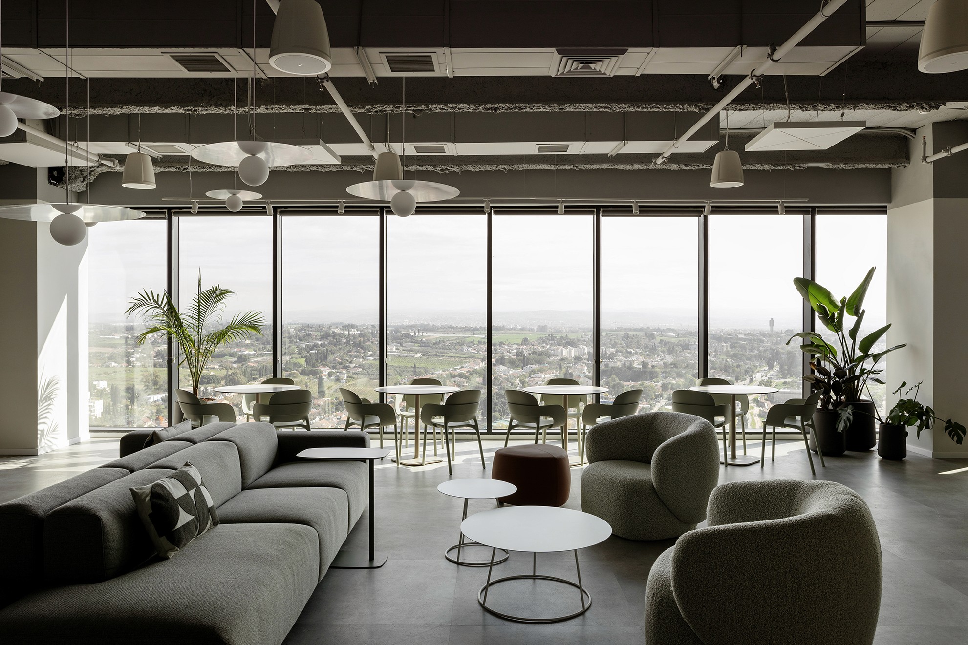 חלל עבודה שיתופי עם חלונות מסך (Curtain Walls) למקסימום אור טבעי וגופי תאורה אקוסטיים מעגליים המרככים את החלל