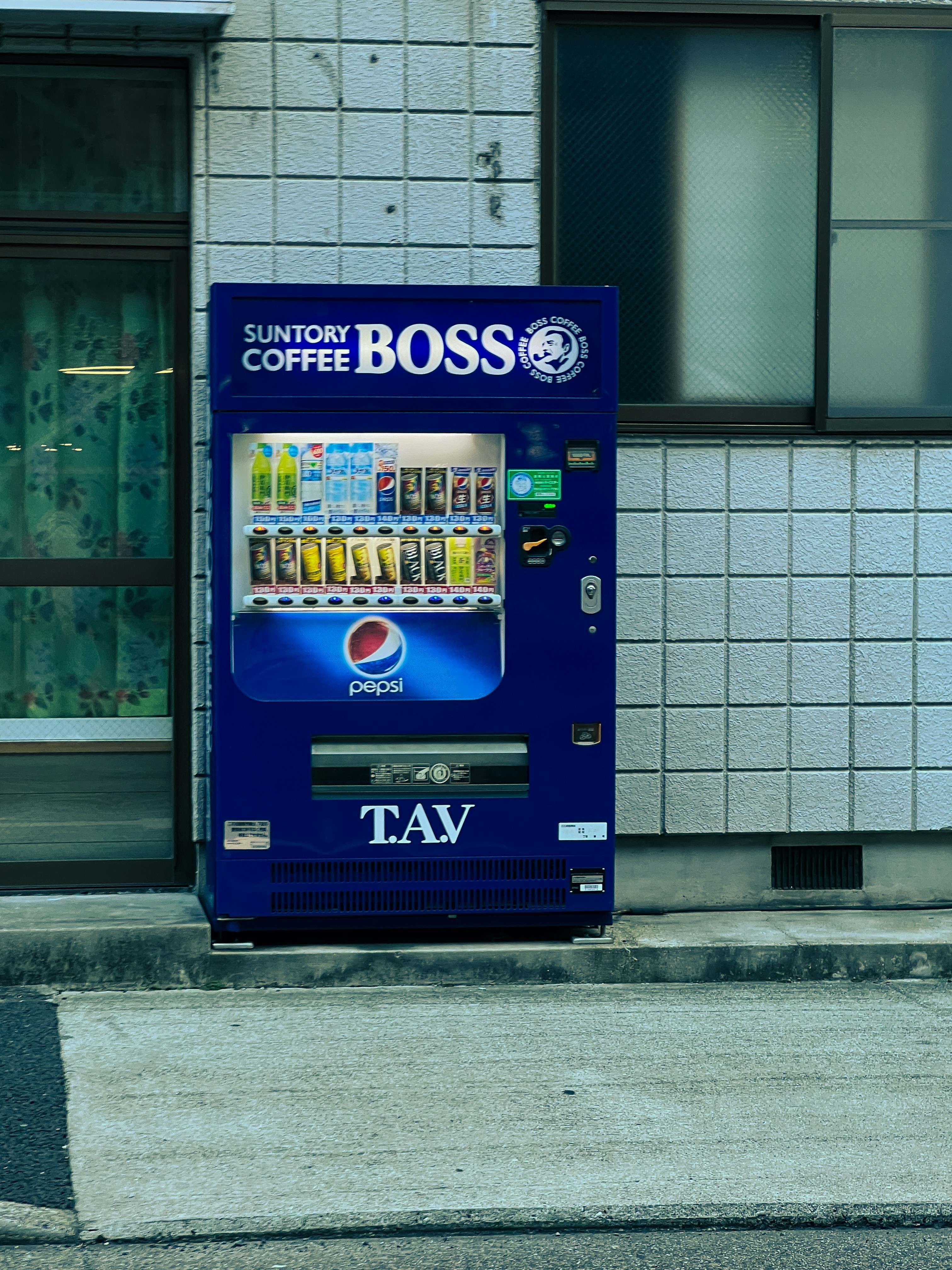 A blue vending machine sitting on the side of a road
