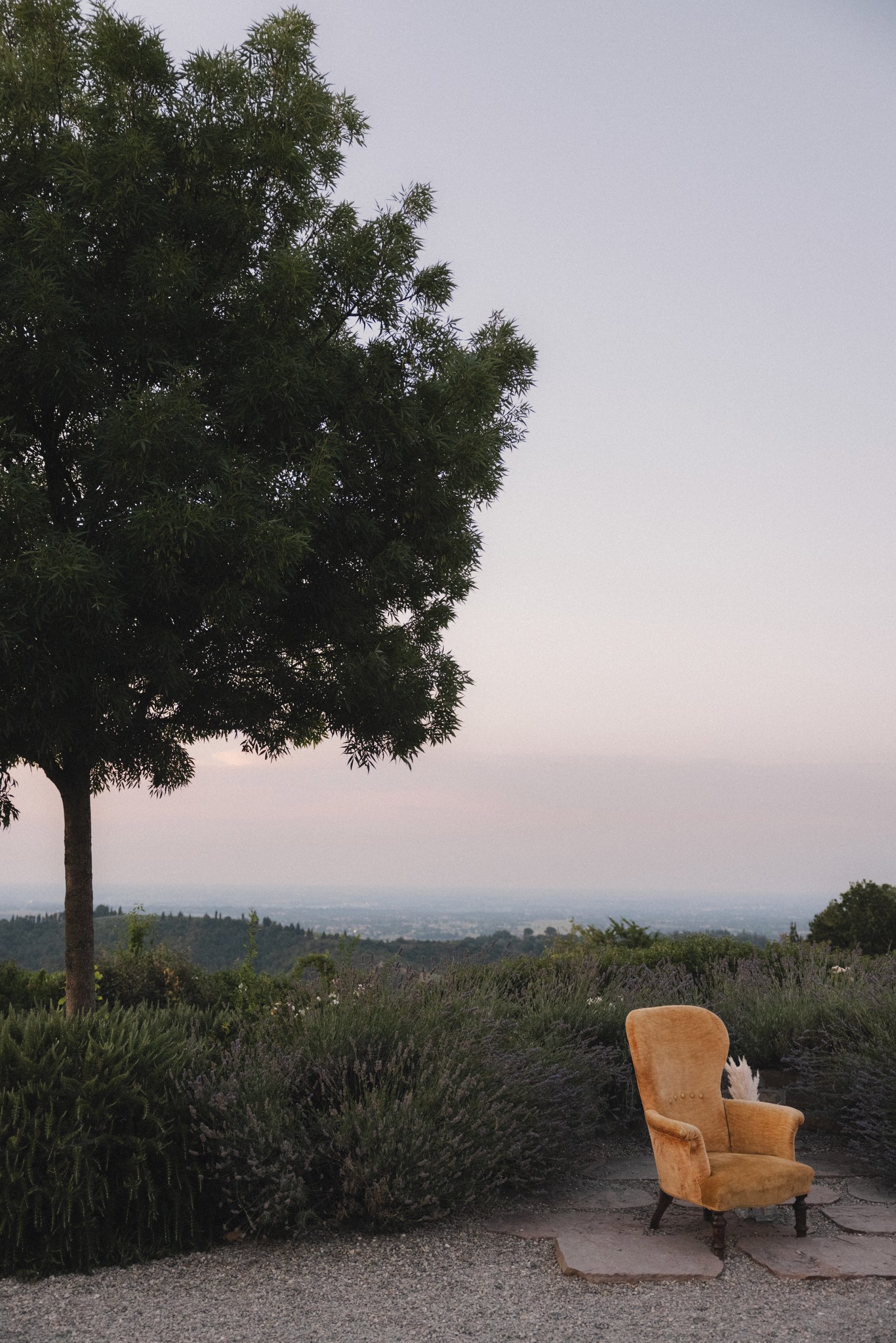 Sedia vintage gialla in mezzo al prato al tramonto, paesaggio collinare sullo sfondo nel Parco di Montebello