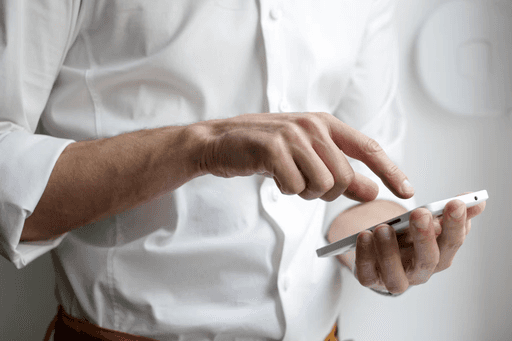 Close-up of a person in a white shirt using a smartphone, potentially searching for legal information or consulting with an AI legal assistant