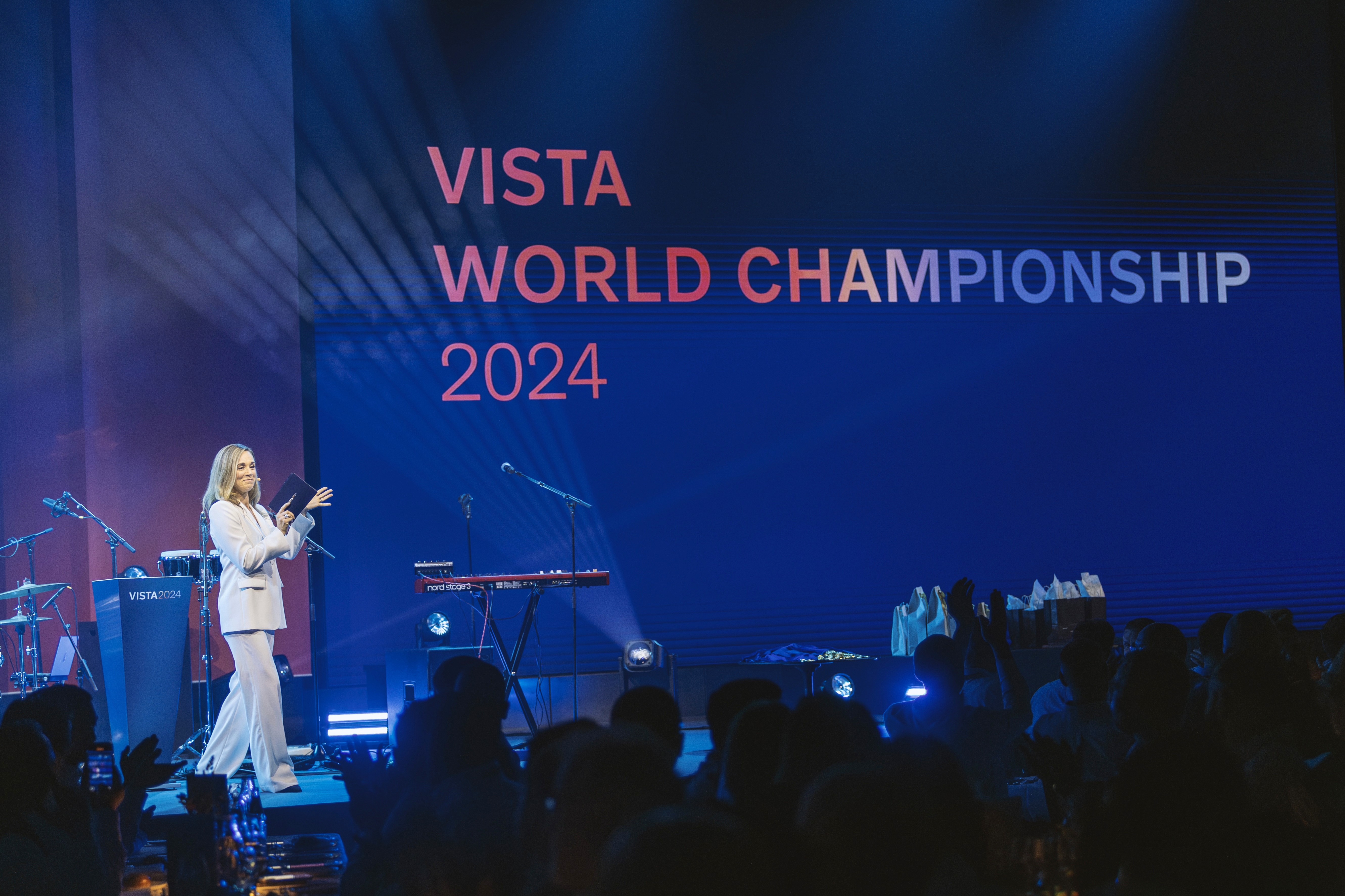 En presentatör står på scenen framför en stor publik