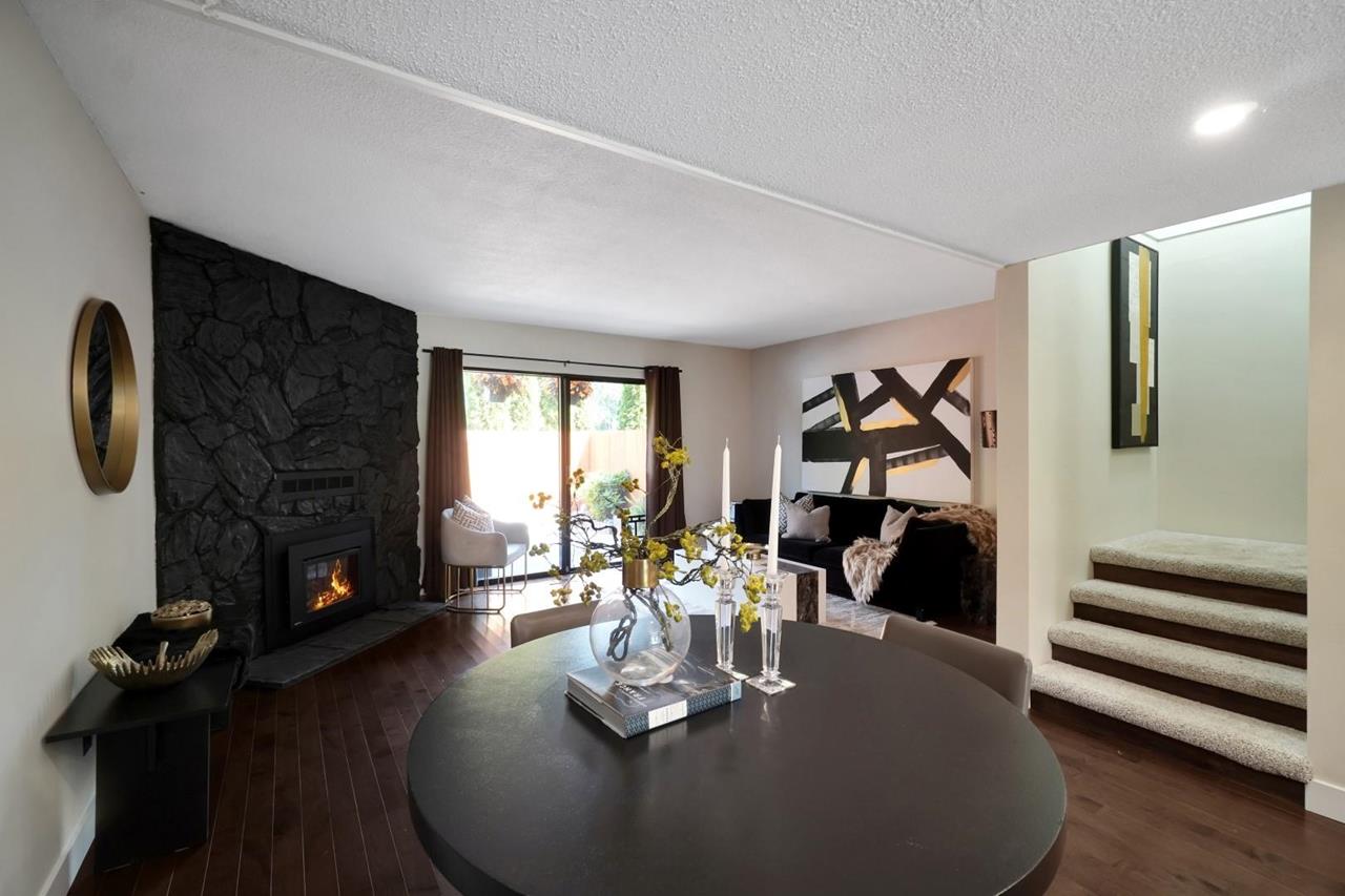 Modern interior view of a room featuring a dining table, large windows, and a sleek staircase.