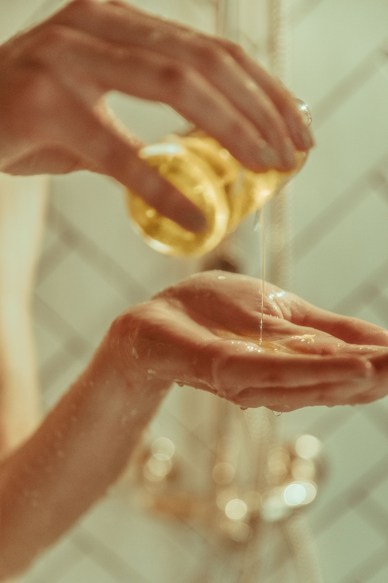 Warm-toned, soft-focus photography of golden facial oil being poured into a palm. This lifestyle art direction emphasizes the sensory experience of Krayna’s vegan cosmetics, showcasing the studio’s skill in beauty industry art direction.