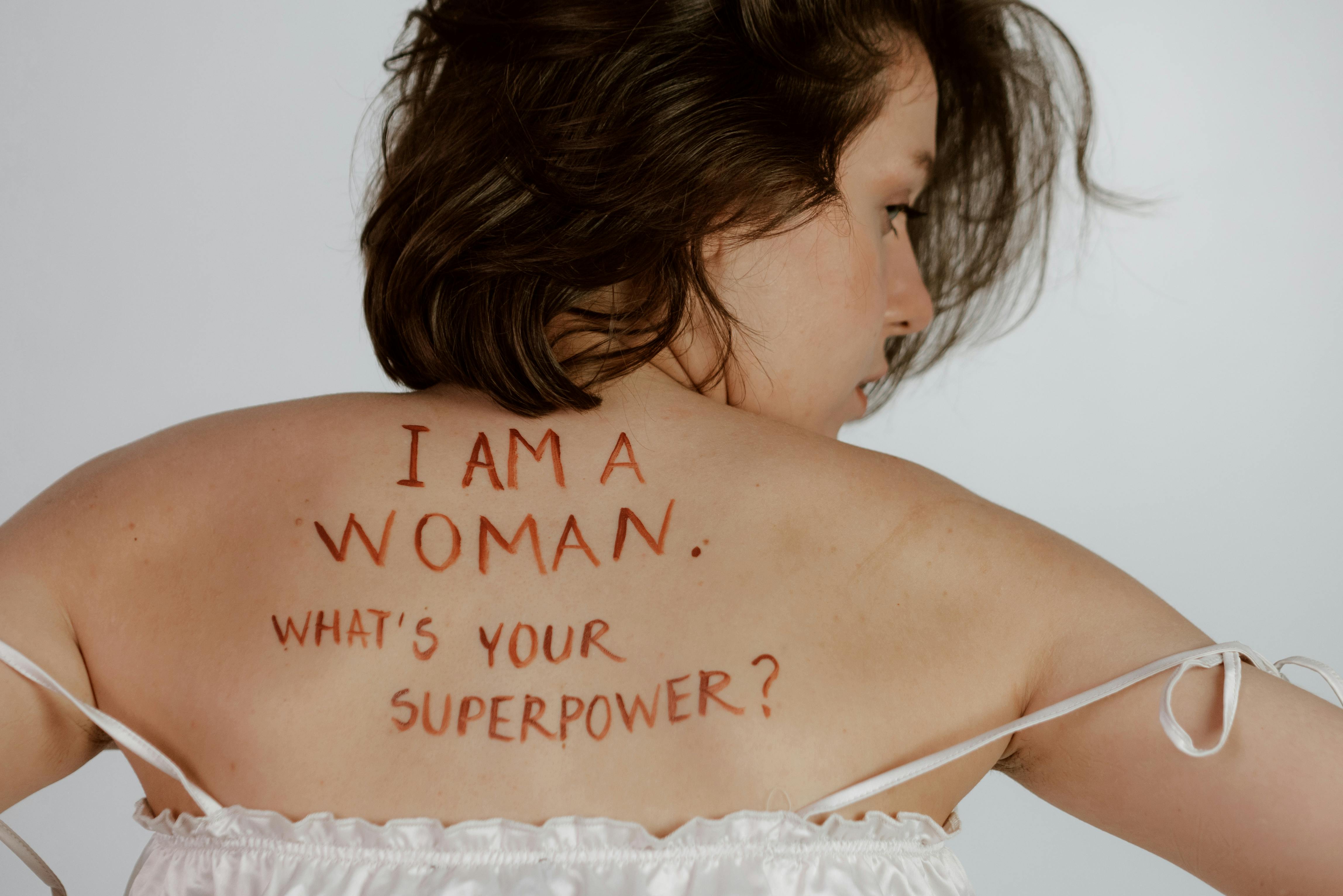 A woman is back to the camera with_I am a woman what is your superpower_written on her back