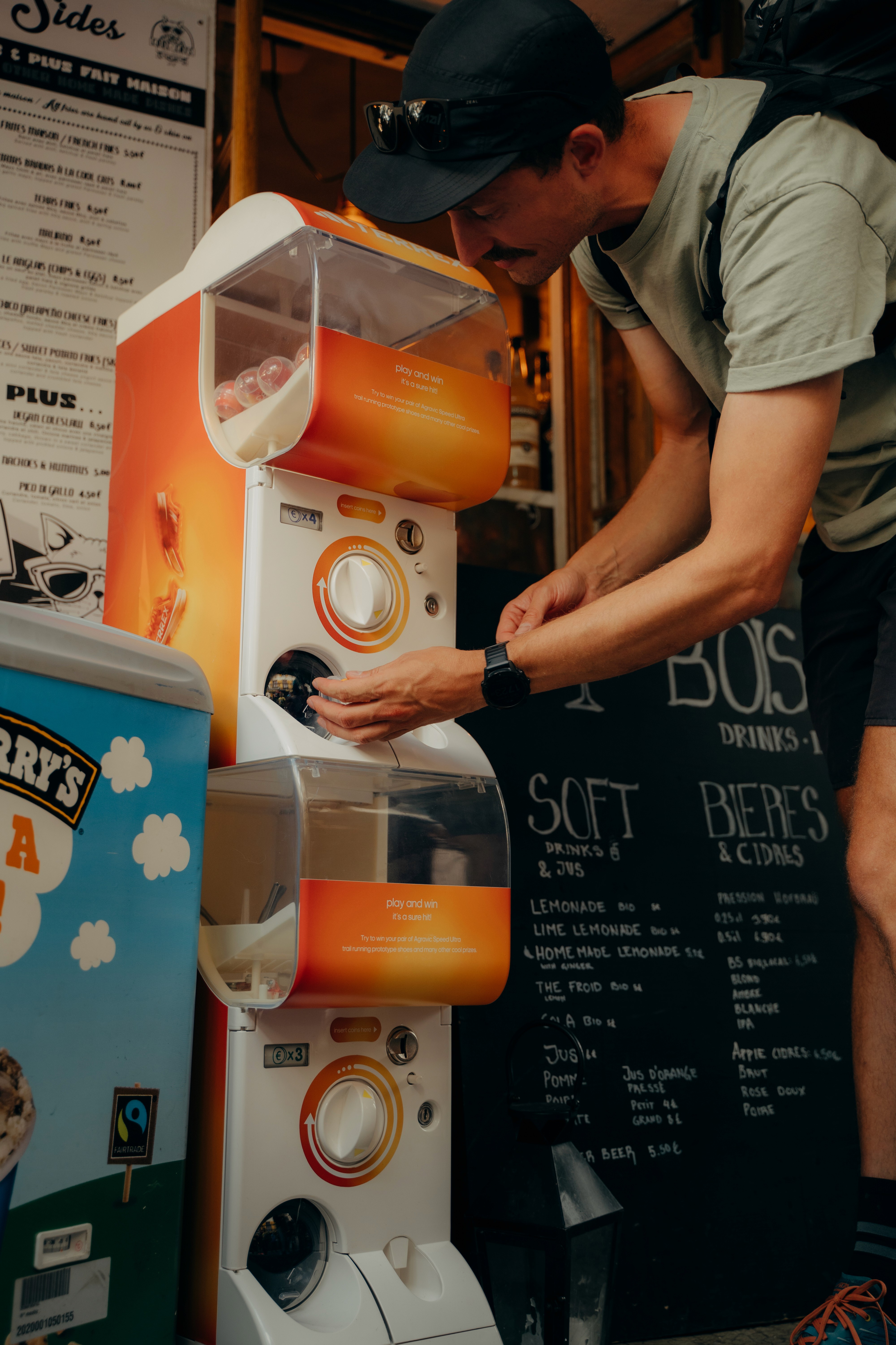 Participant trying the Adidas Terrex "Play and Win" capsule machine set up in a Chamonix café