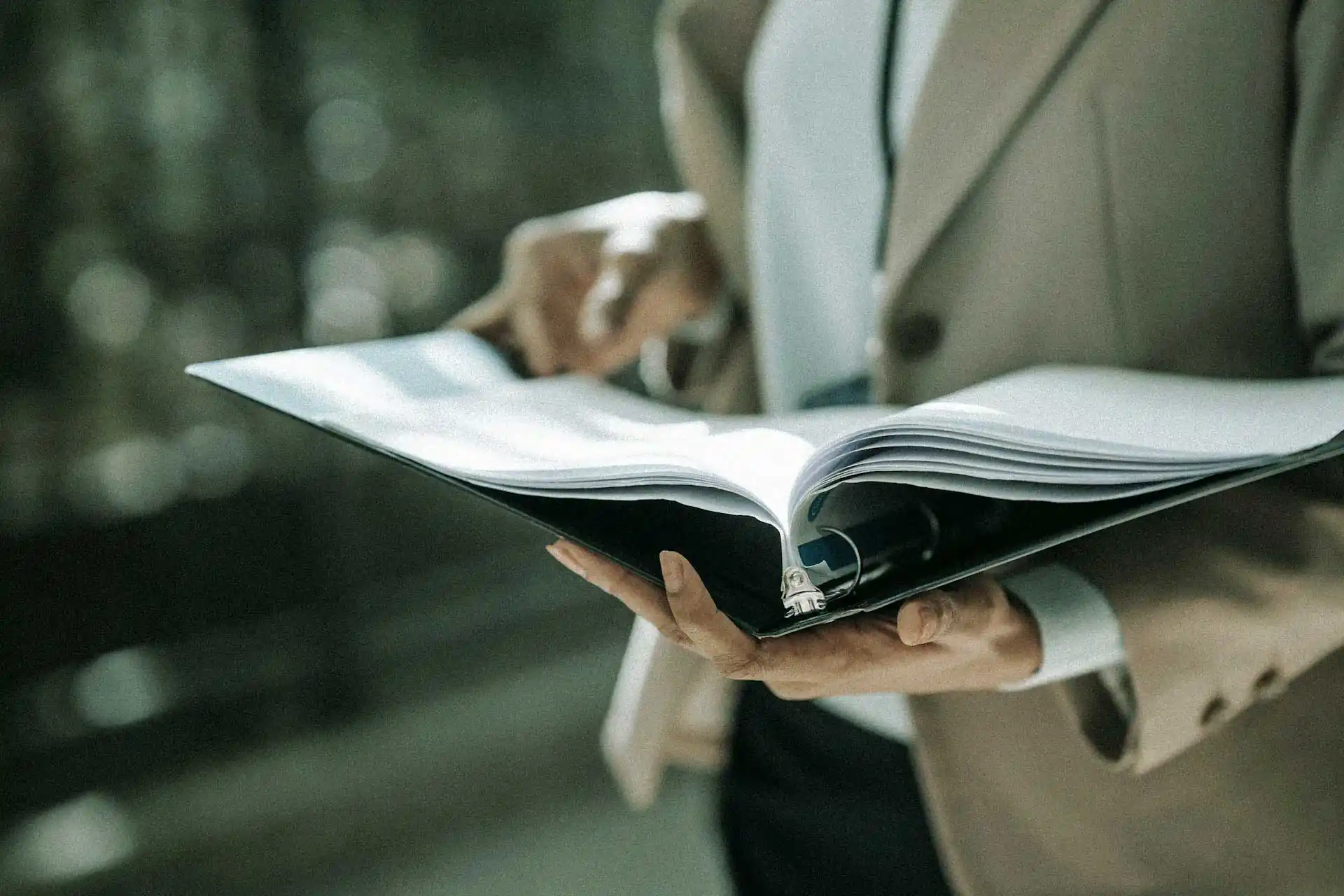 Person holding open a binder with papers.