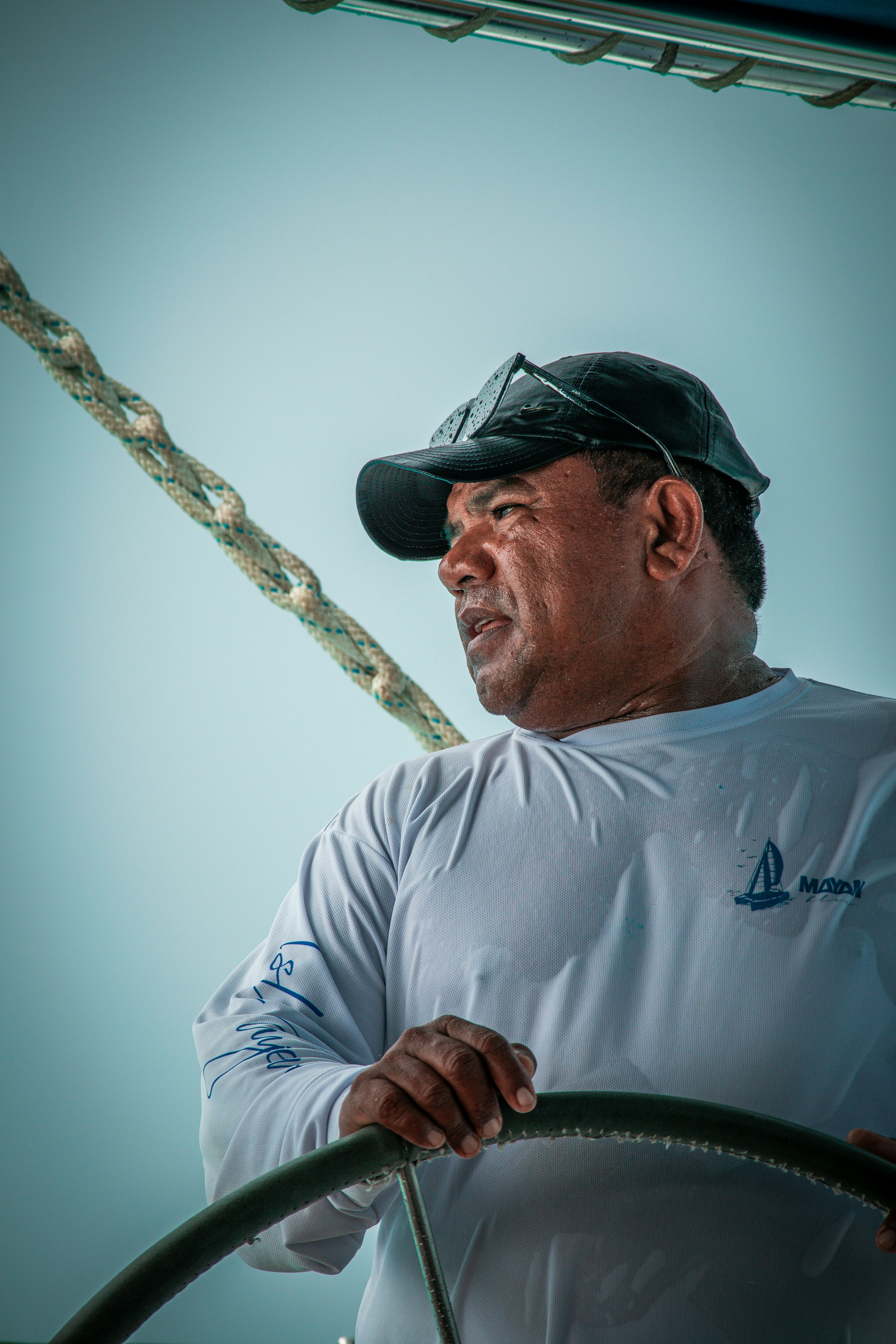 a man in white shirt holding a rope on top of a boat