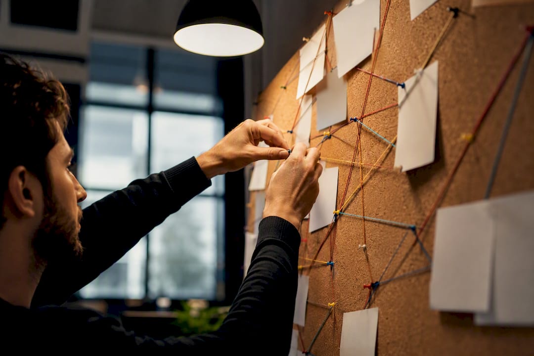 Hands mapping workflow audit on corkboard