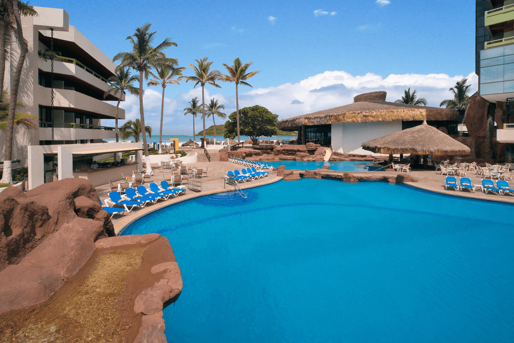 Couple standing on a balcony with binoculars in hand looking out over the ocean
