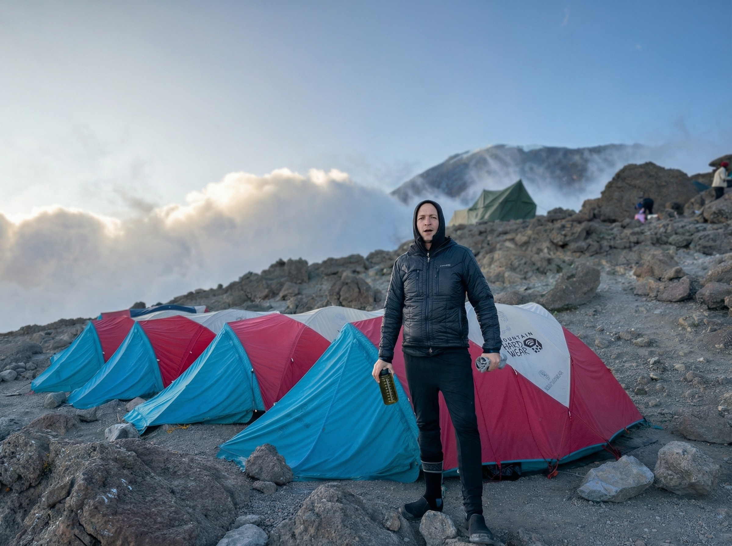Traveler sitting on desert rocks during the Desert Sky tour in AlUla, smiling and holding binoculars.