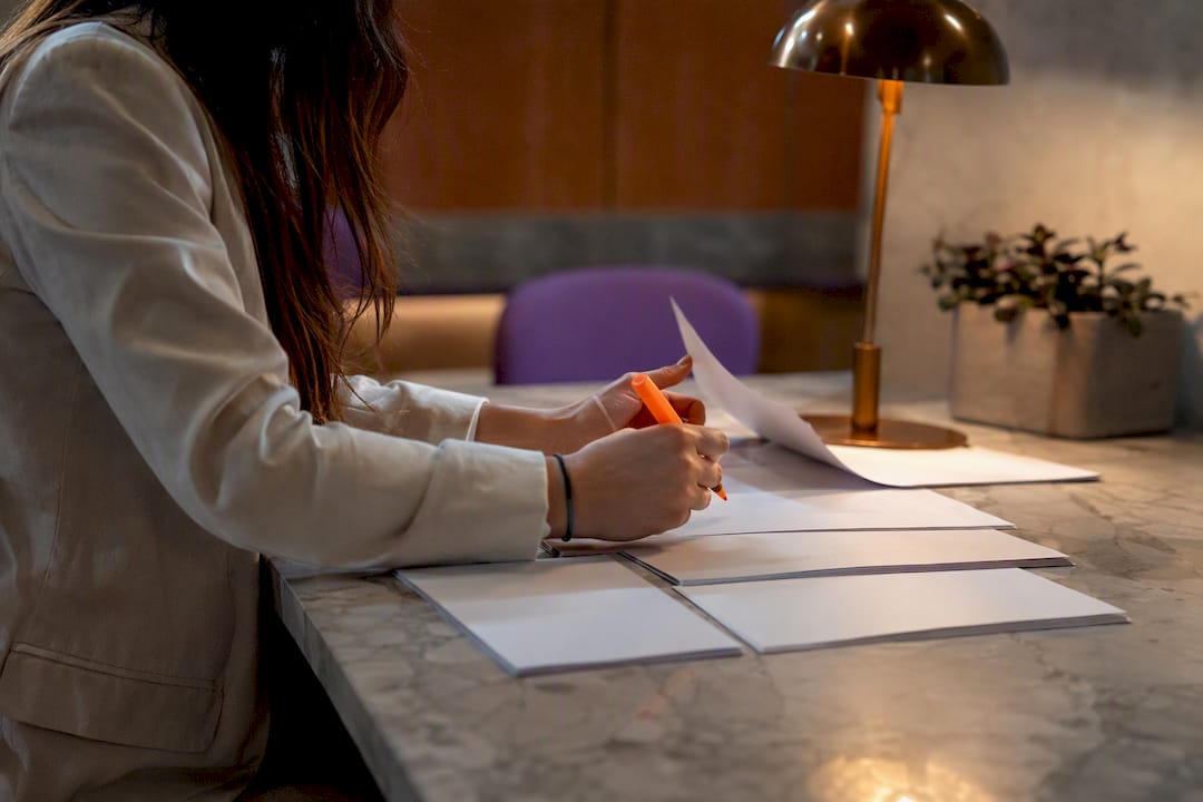 Hands sorting blank timesheets under lamp