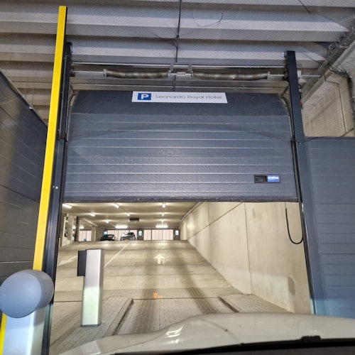莱昂纳多皇家酒店的地下停车场入口，部分卷帘门已经打开，显示通向内部停放车辆的坡道。