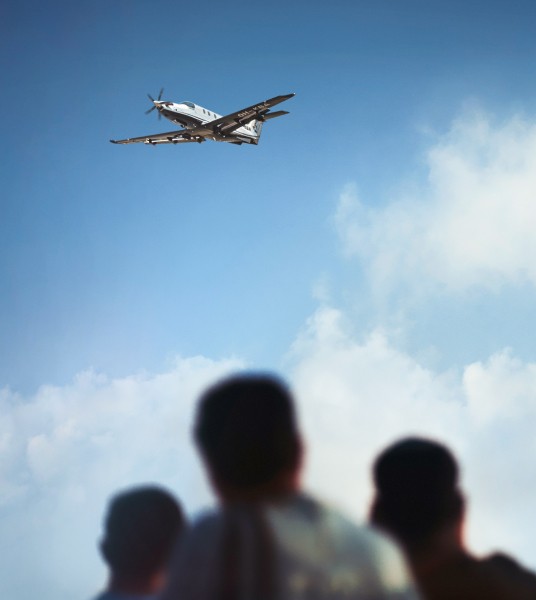 Pilatus Pc-12 flying overhead against a blue sky, viewed from below