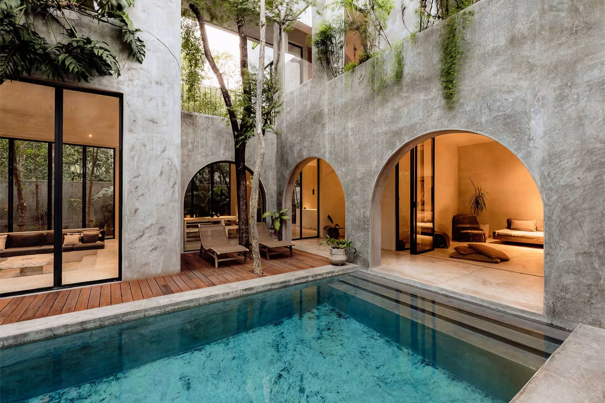 Central courtyard of Casa Shalva featuring signature concrete arches, a swimming pool, and preserved trees integrated into the design.