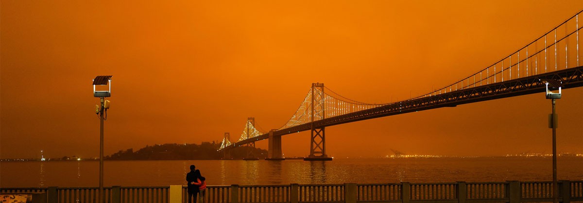 A bridge silhouetted against a deep orange sky, creating a dramatic and moody landscape.