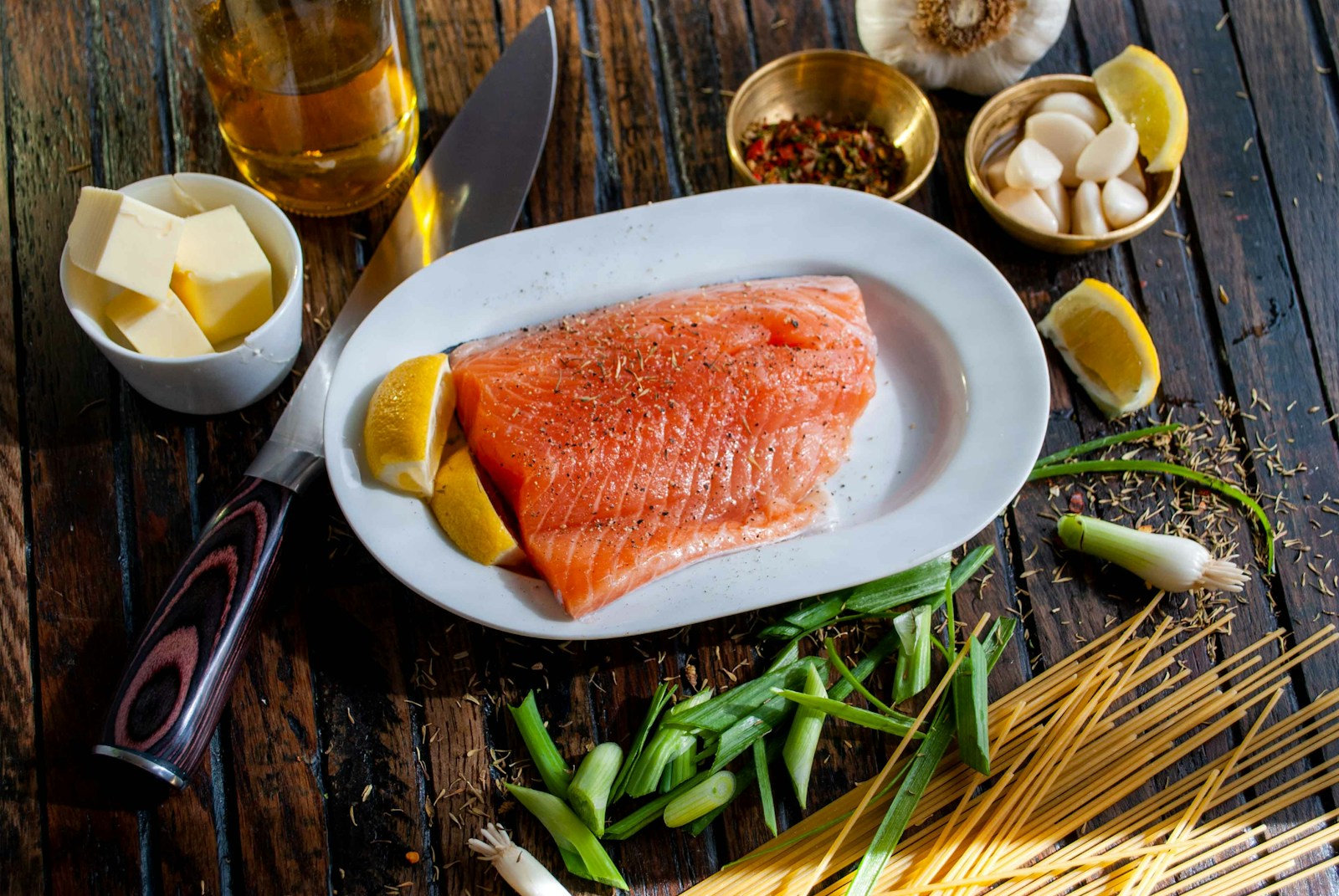 A fresh salmon fillet on a plate with lemon, herbs and other ingredients, representing omega-3-rich anti-inflammatory foods