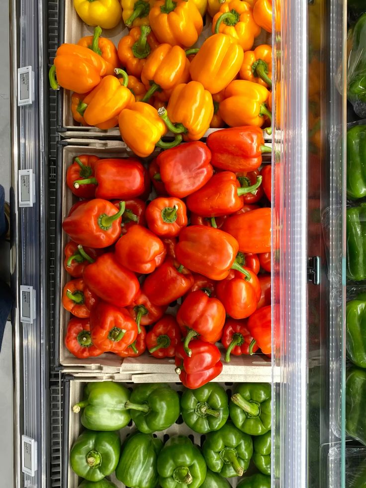 "Fresh red, and green bell peppers neatly arranged in separate wooden crates in a grocery store