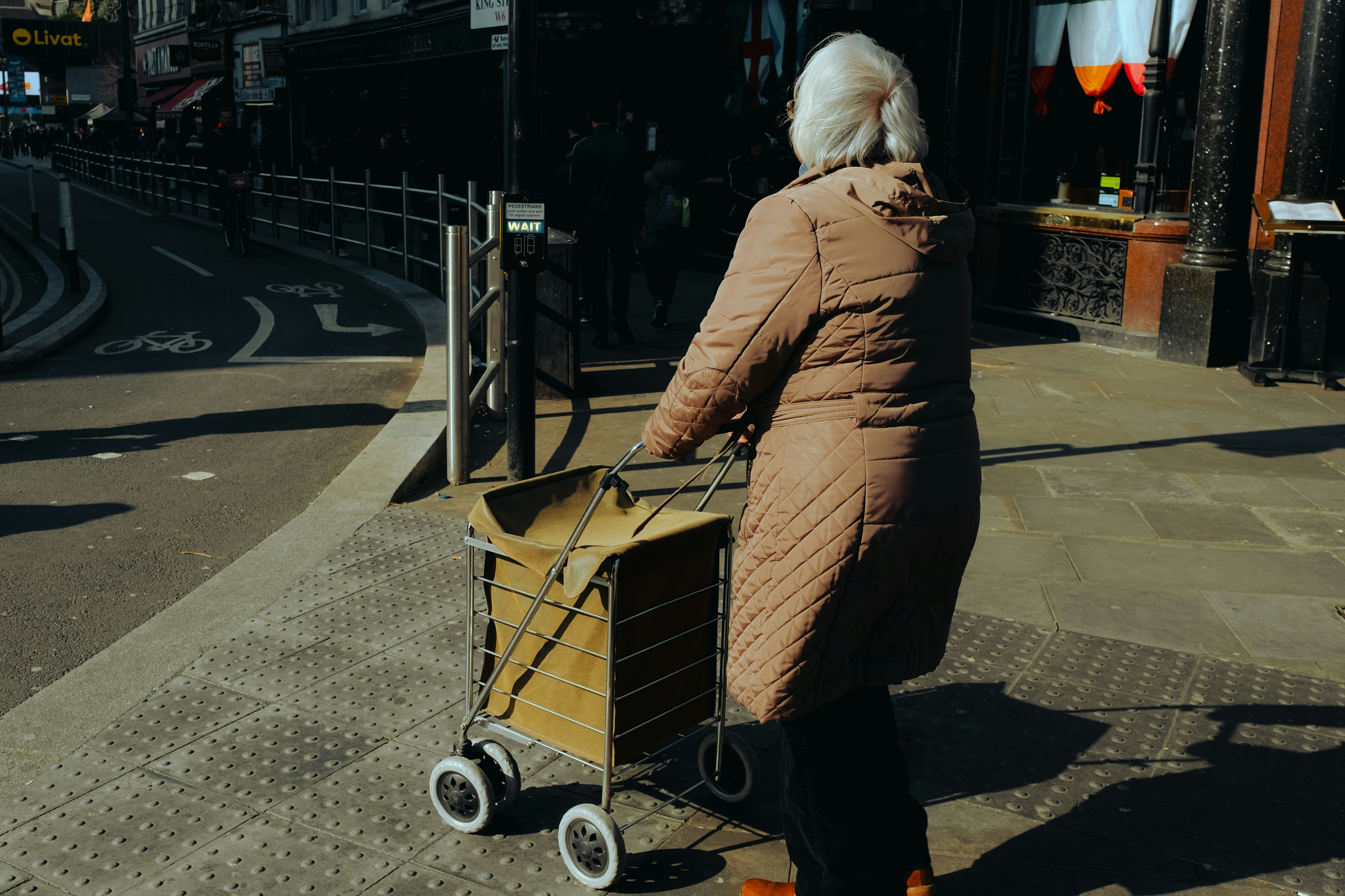 a woman pushing a shopping cart down a street