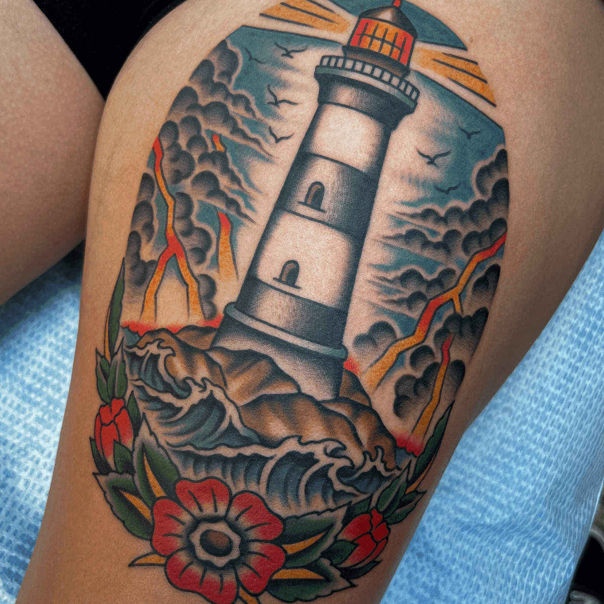 large color tattoo of a lighthouse in a storm