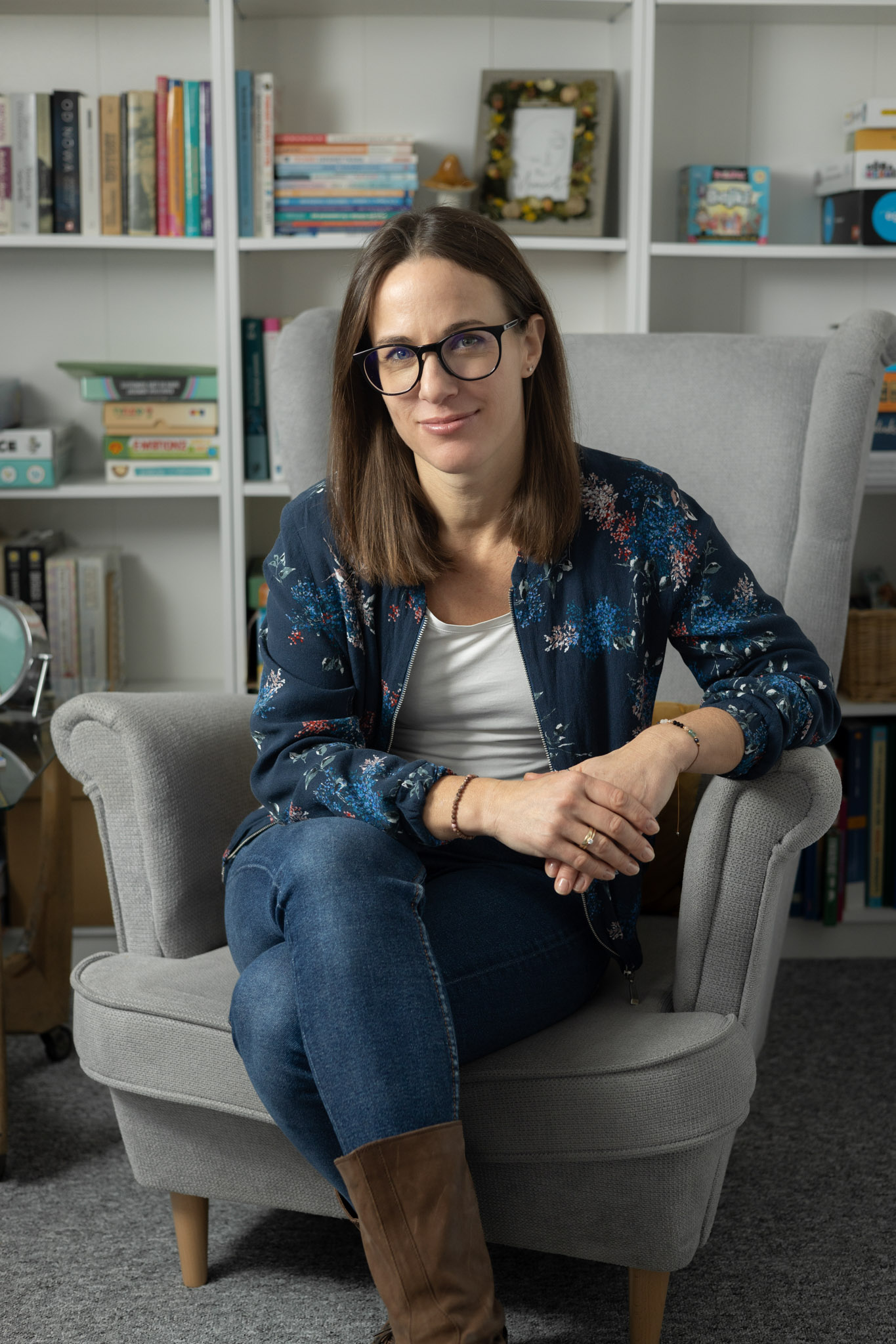 Portret psychoterapeutki Ewy Jasińskiej na tle regału z książkami