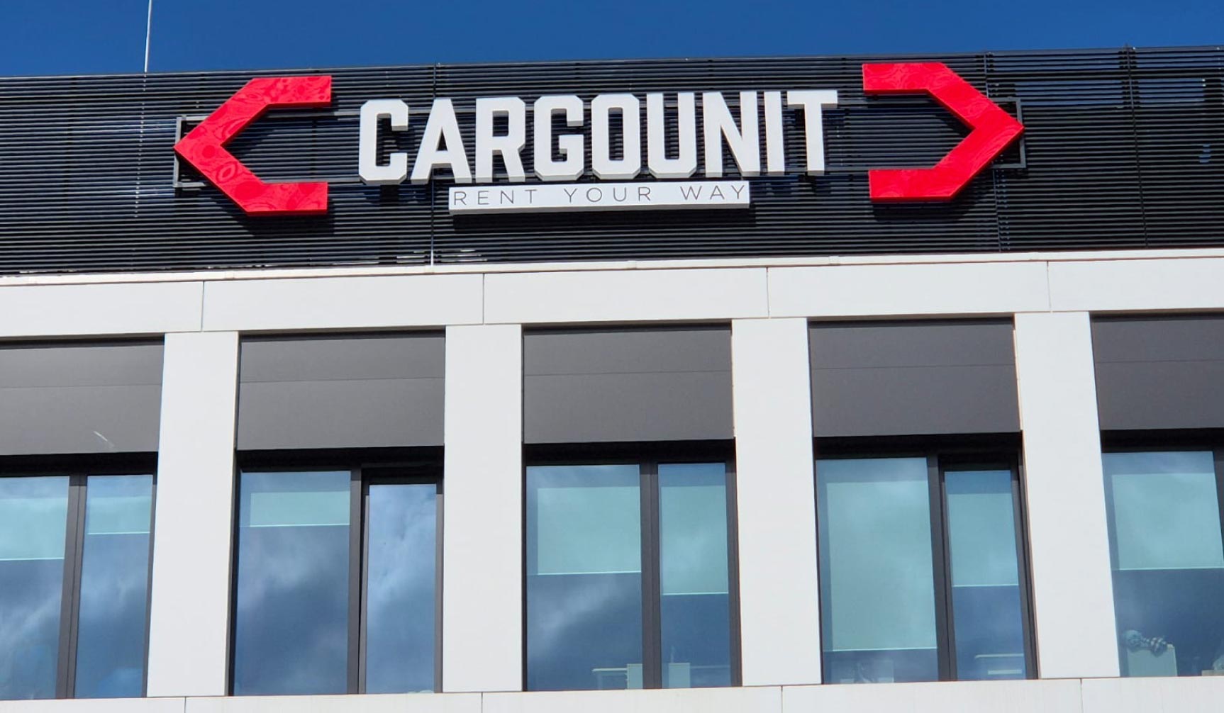 Branding budynku – zbliżenie na podświetlany kaseton reklamowy (logo 3D) nad oknami biura.