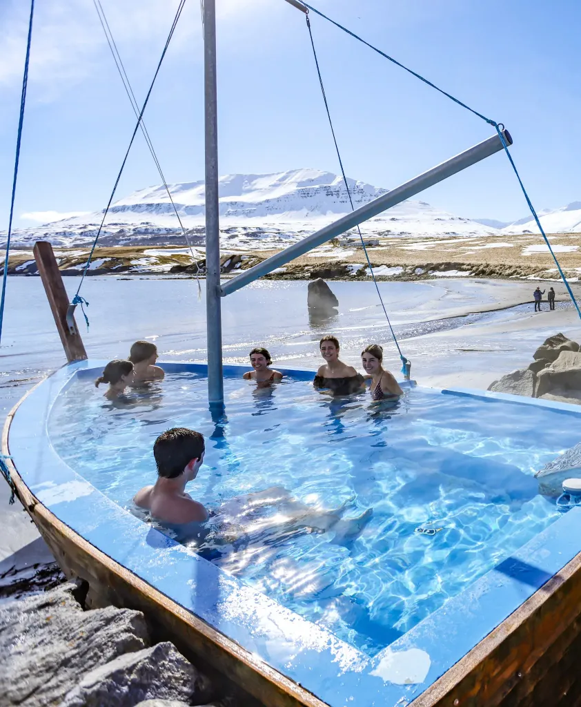 Seaside hot tubs made of stone overlooking the ocean and snowy mountains in Hauganes.