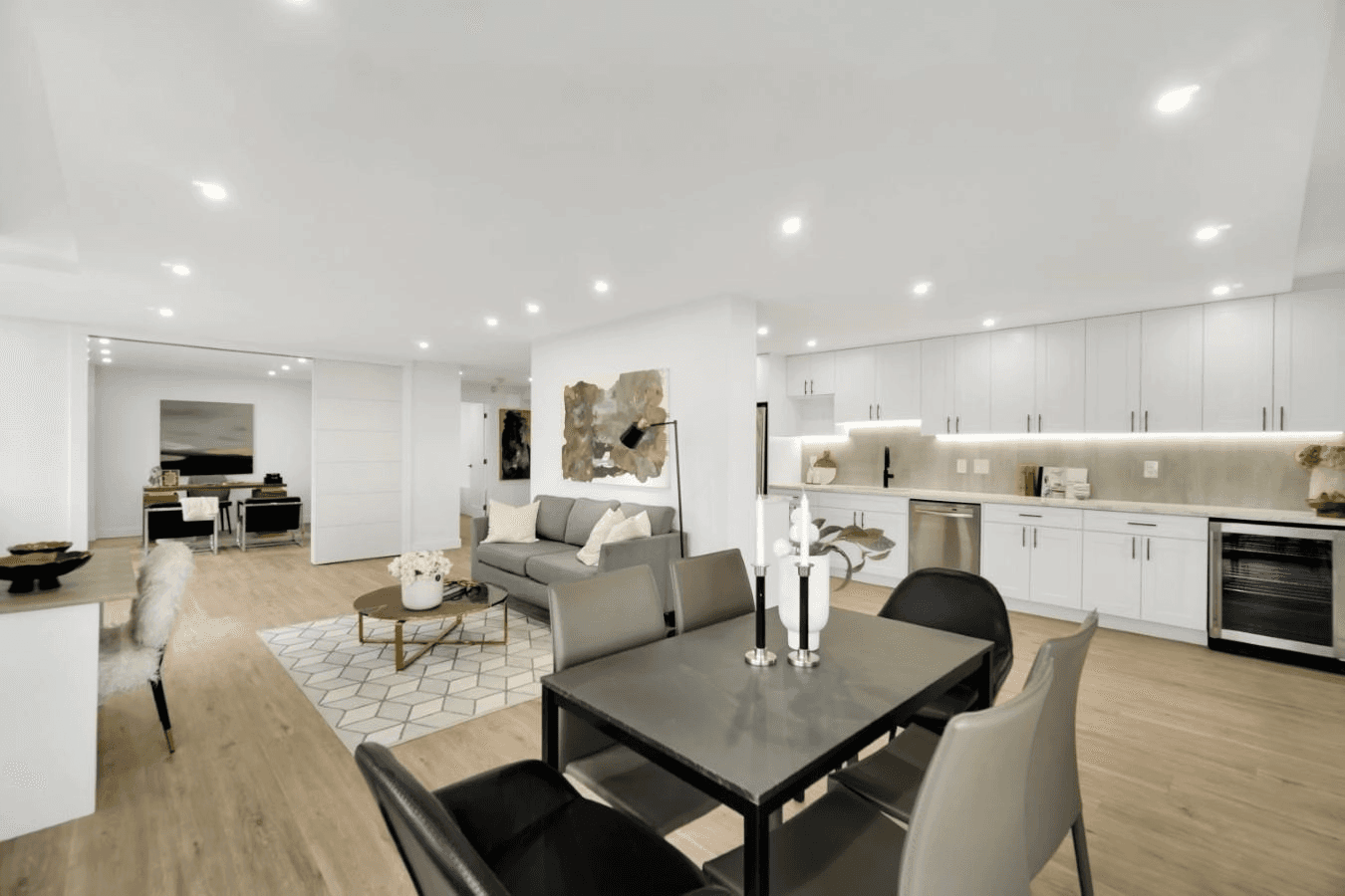 Modern open-concept living and dining area featuring a sleek table, stylish chairs, and contemporary kitchen design.