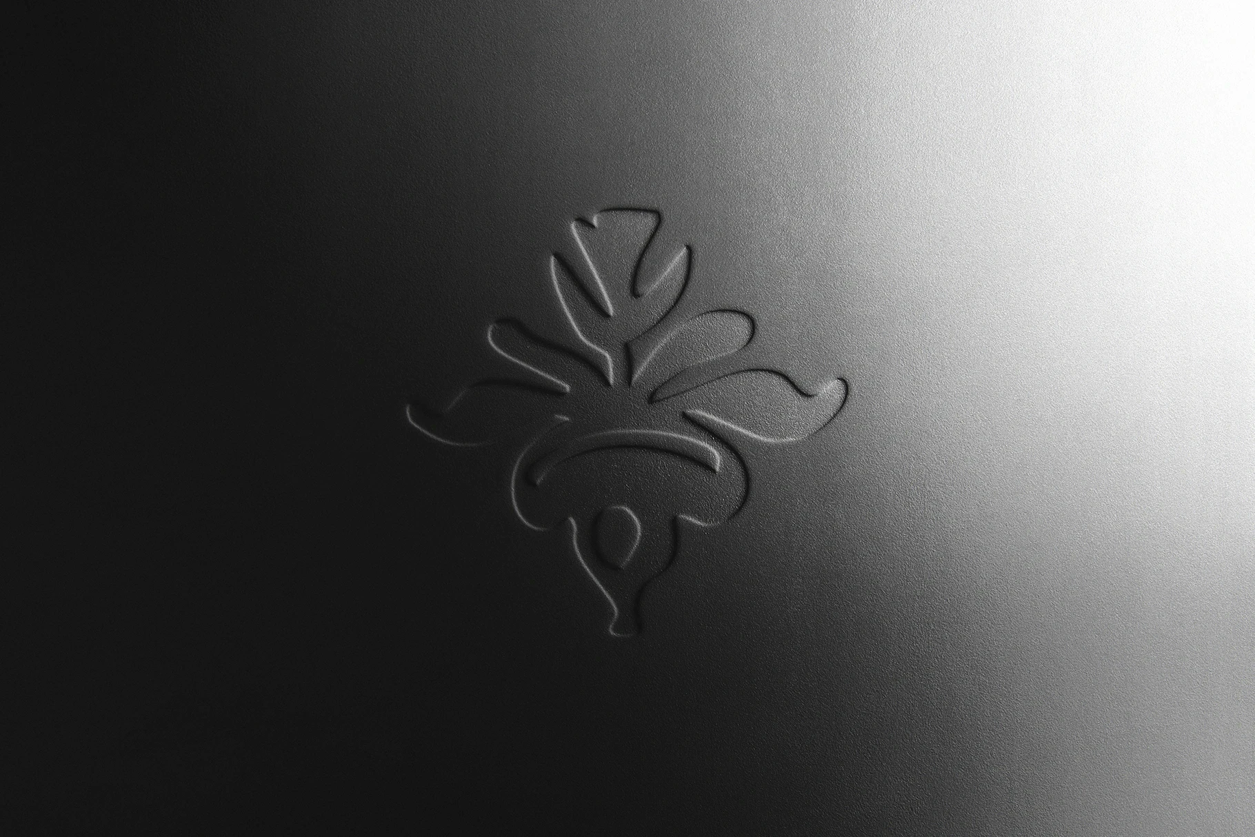 A subtle blind emboss mockup of a leaf icon on dark, textured paper.
