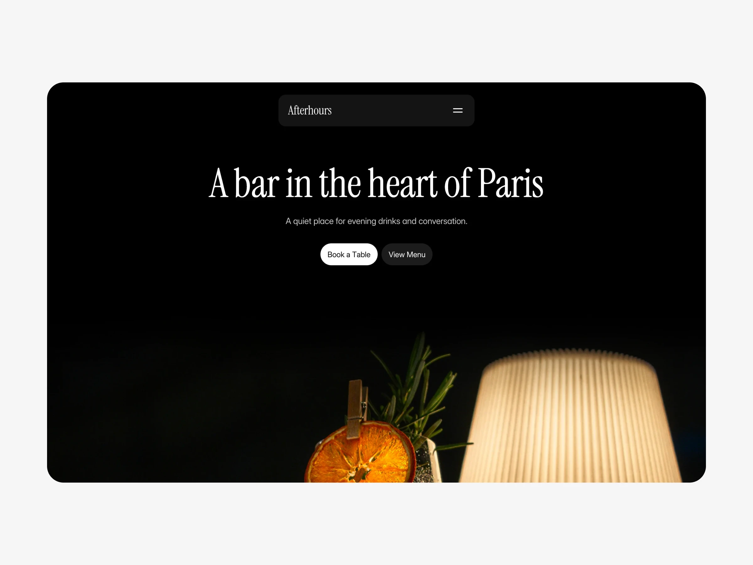 Dark bar interior with a cocktail glass and table lamp, showcasing a restaurant website template hero section.