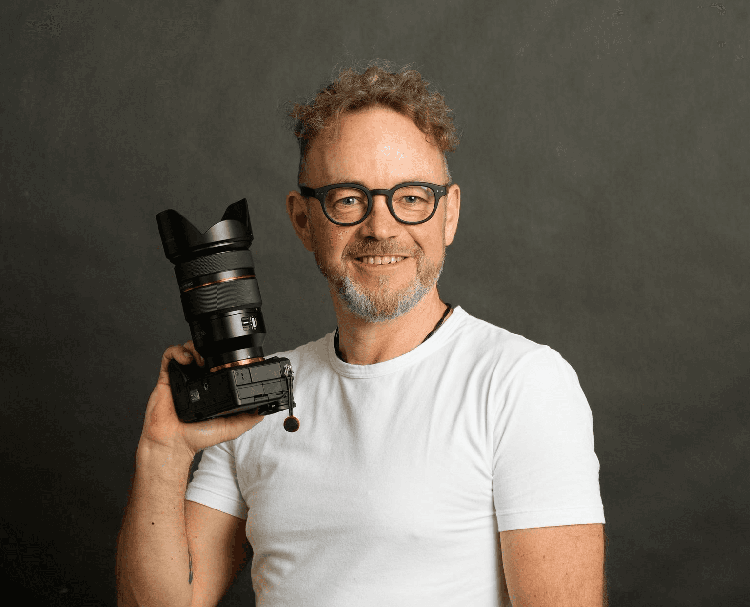 A large group photo of diverse team members gathered in an industrial-style space with arched ceiling.